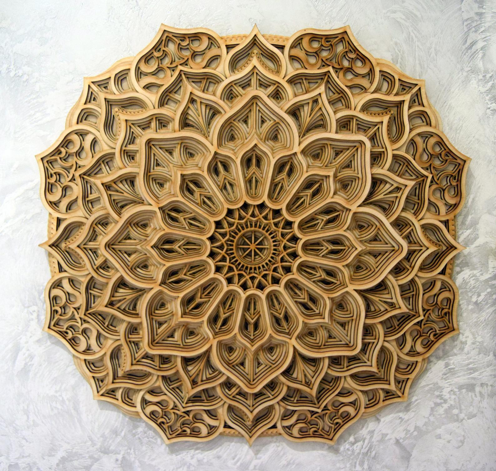 A circular wooden mandala with geometric patterns, featuring intricate cut-outs and a central point.